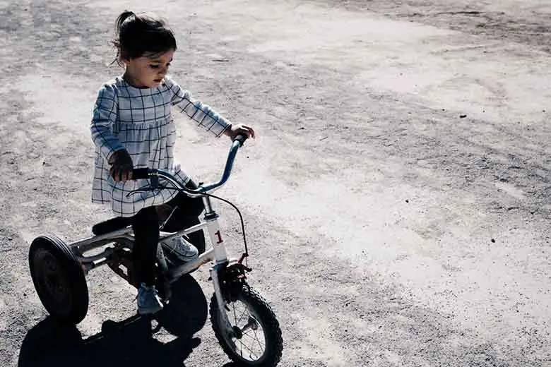 une petite fille sur un tricycle